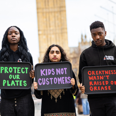 A group of young people are holding up black trays painted with slogans outside of Westminster in London