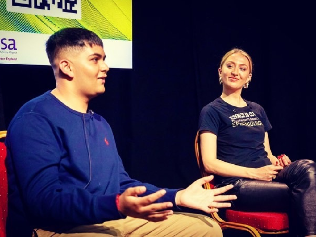 Dev, a young person and Dolly, Bite Back's Chair of Trustees are sitting and speaking at a panel.