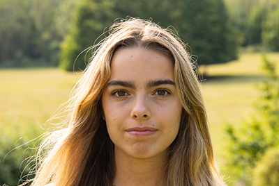 A young white woman with long blonde hair is looking straight into the camera.