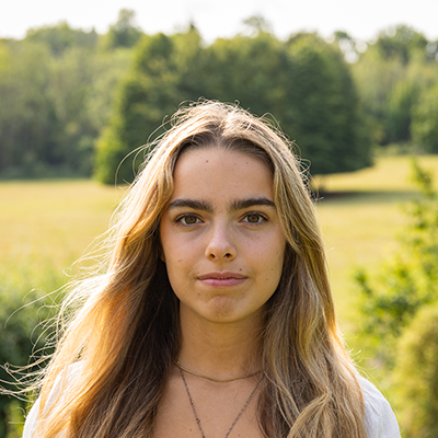 A young white woman with long blonde hair is looking straight into the camera.