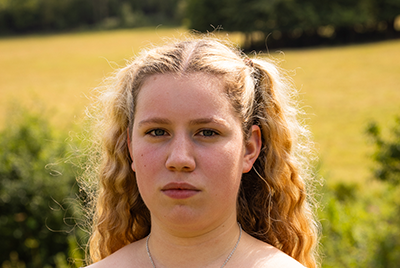 A young white woman with curly blonde hair is looking powerfully into the camera.