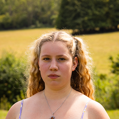 A young white woman with curly blonde hair is looking powerfully into the camera.