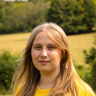 A young white woman with long blonde hair is gazing into the camera with a serious expression.
