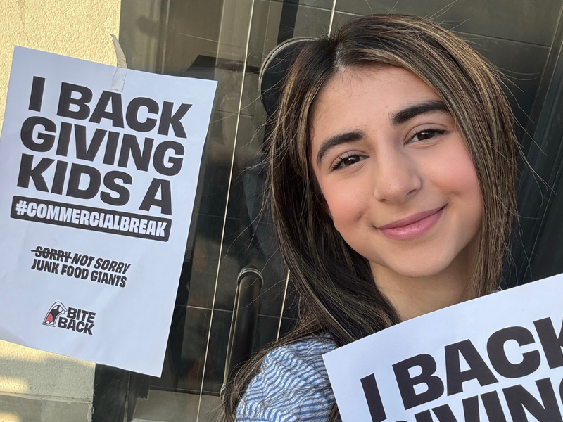 Bite Back activist Prusha takes a selfie with our poster which reads I back giving kids a commercial break sorry not sorry junk food giants
