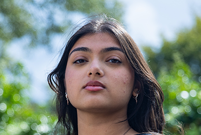 A young South Asian woman is looking into the camera with a powerful expression