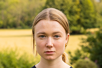 A young white woman with her hair pulled back into a ponytail is staring fiercely into the camera