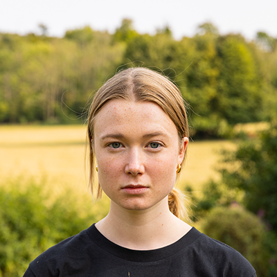 A young white woman with her hair pulled back into a ponytail is staring fiercely into the camera