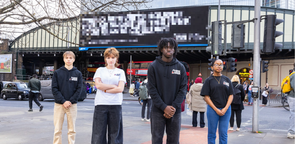 Four Bite Back activists stand in front of our billboard in London Bridge, the image has been edited to pixelate our billboard to represent it being censored by the advertising industry.