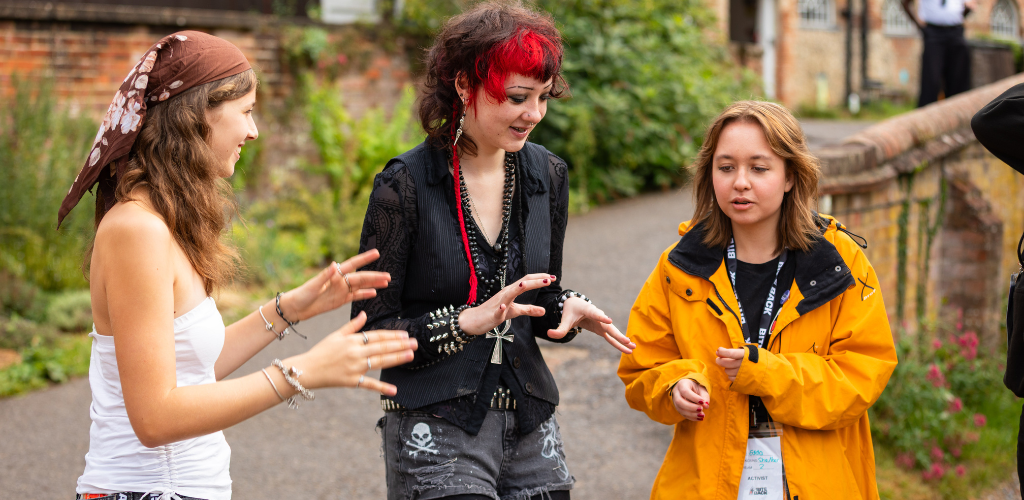 Three young people are playing a game with their hands, similar to rock paper scissors