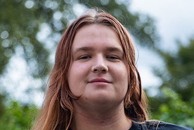 A young white woman with light brown hair flowing past her face is looking powerfully into the camera