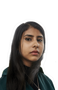 Nabeeha a young brown skinned woman with long dark hair and dark eyes. She has full eyebrows and lips and is wearing a dark green jumper with a golden pendant necklace. She is wearing a serious expression showing she is ready to tackle a food system set up to fail us all.