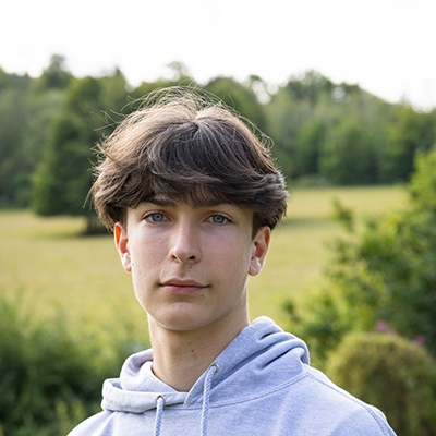 A young white man with cropped brown hair is looking into the camera with a powerful expression.