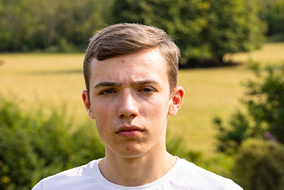 A young white man with short hair is gazing sternly into the camera.