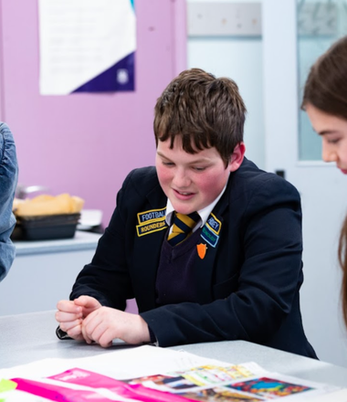Three school students and an adult sit around a classroom table taking part in a Bite Back in Schools activity, they are all smiling