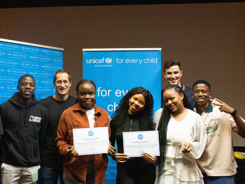A group of young activists stood with D&#x27;Arcy, our new CEO, and James, our former CEO in front of UNICEF banners
